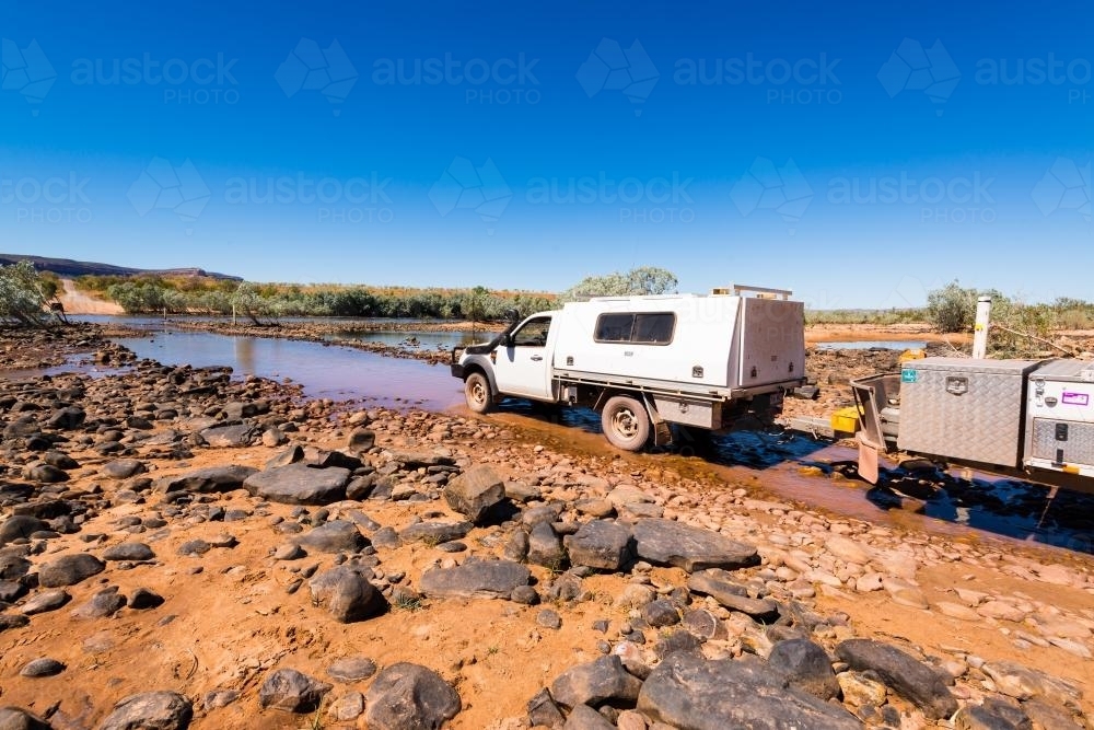 4WD vehicle towing a camper trailer crossing the Pentecost River - Australian Stock Image