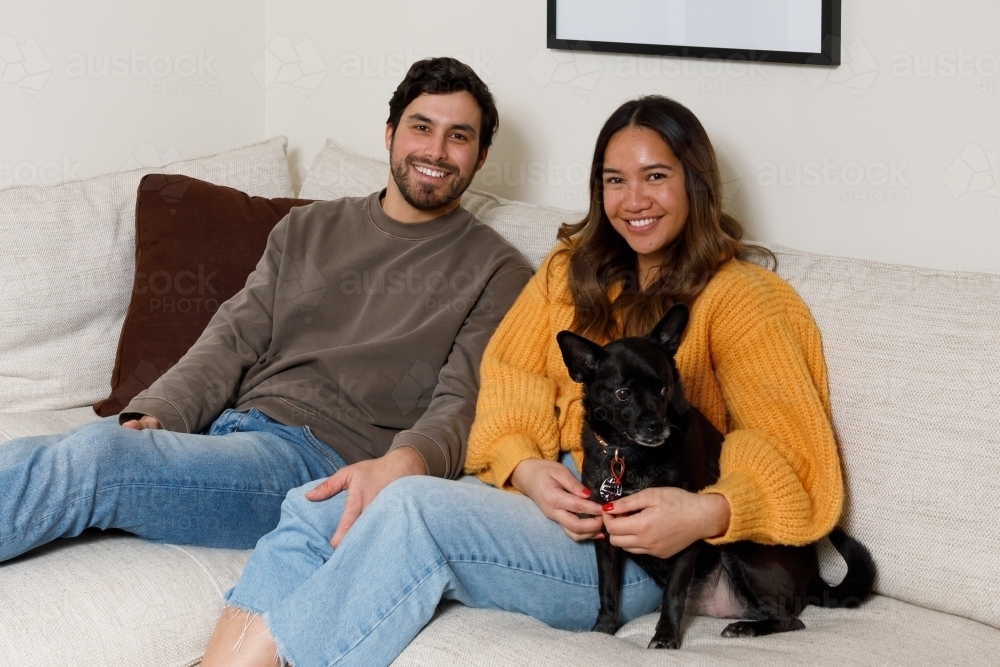A couple at home on a couch with their dog - Australian Stock Image