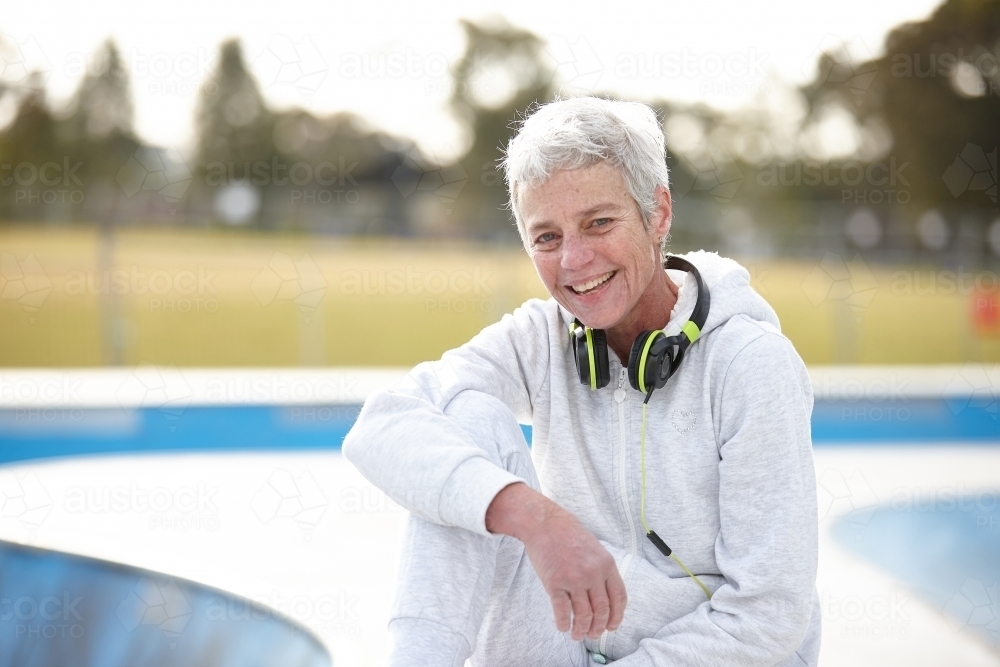 Active senior laughing listening to music with headphones - Australian Stock Image