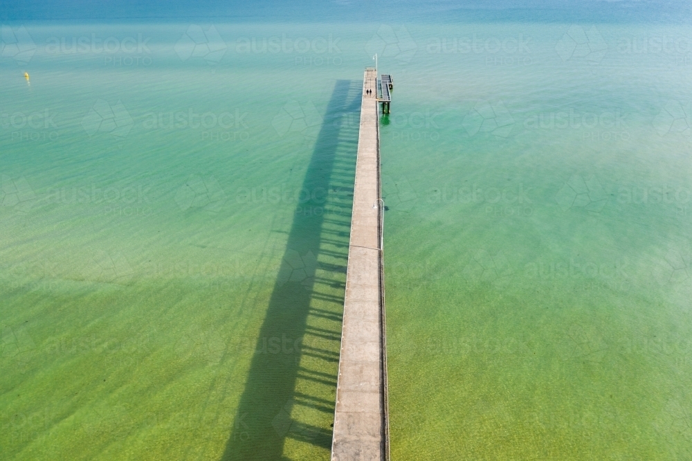Aerial view of a long narrow jetty out over a calm bay - Australian Stock Image