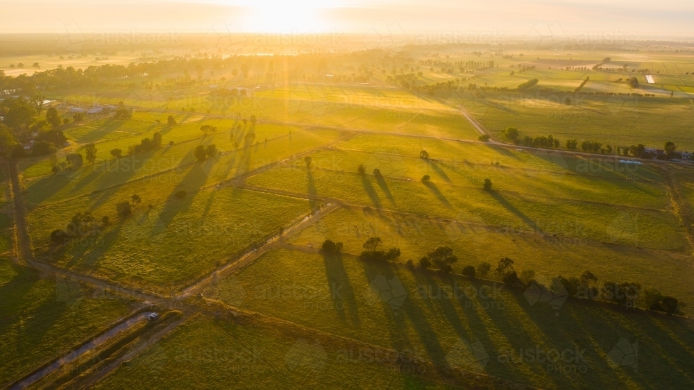 Aerial view of golden morning light and long shadows over green farmland - Australian Stock Image