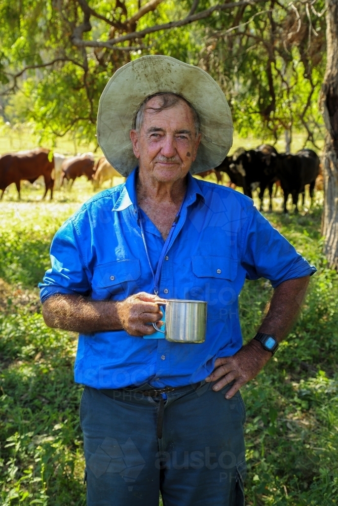 An old farmer enjoying his morning cup of tea in the shade of trees. - Australian Stock Image