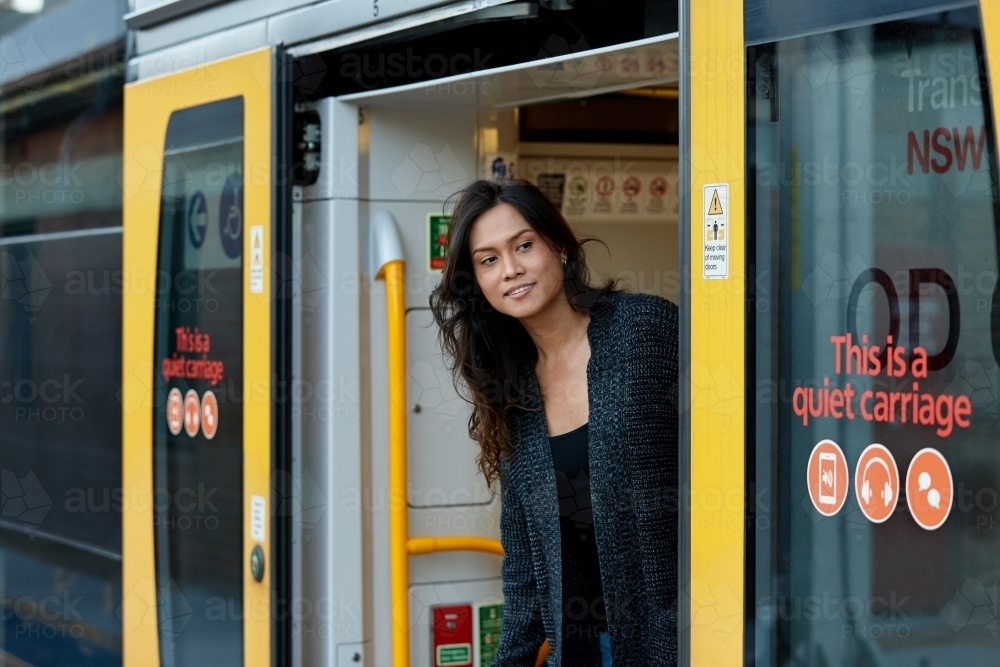 Asian woman looking outside of train at train station - Australian Stock Image