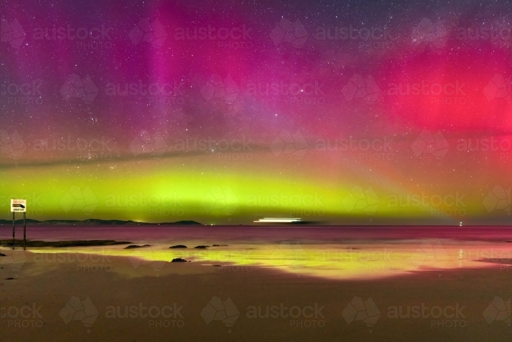 Aurora Australia illuminating the night sky and reflecting on a wet sandy beach - Australian Stock Image
