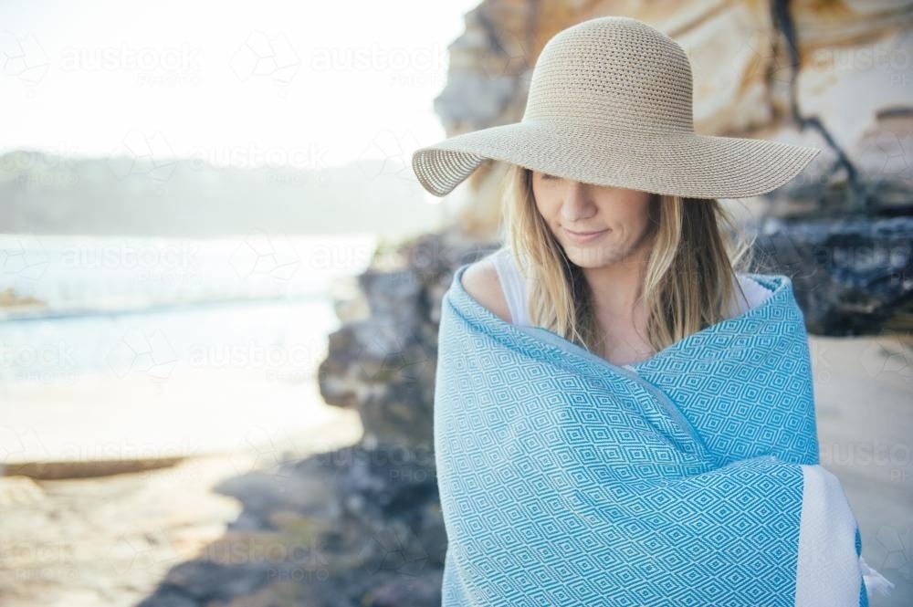 Blonde woman wrapped in turkish towel wearing a beach hat - Australian Stock Image
