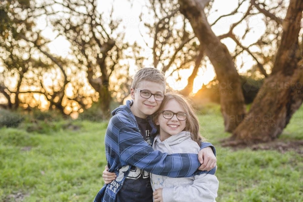 Brother and Sister hugging in afternoon sun - Australian Stock Image