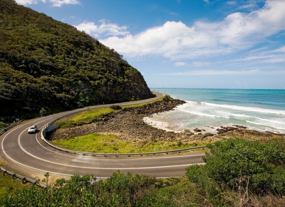 Car driving around a horseshoe bend on a coastal road - Australian Stock Image