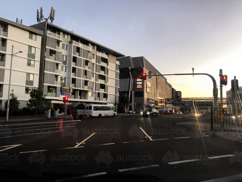 city intersection at dusk with busy asphalt road, tall buildings and cars - Australian Stock Image
