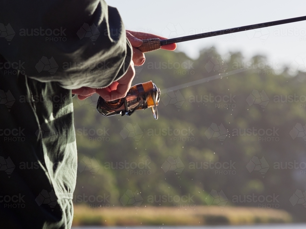 Close up of Man winding Fishing Reel while Holding a Rod - Australian Stock Image