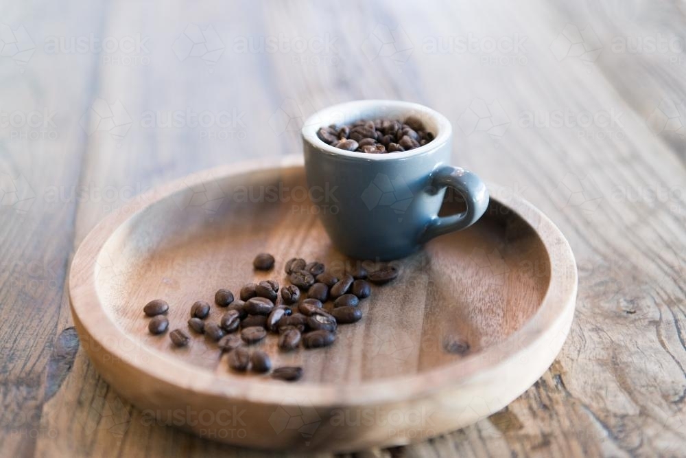 Coffee beans and cup on a wooden tray and table - Australian Stock Image