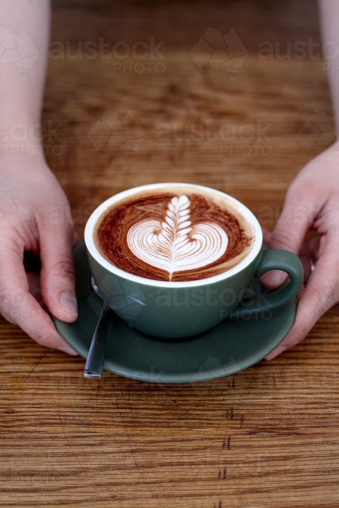 Coffee with froth decoration served on table - Australian Stock Image