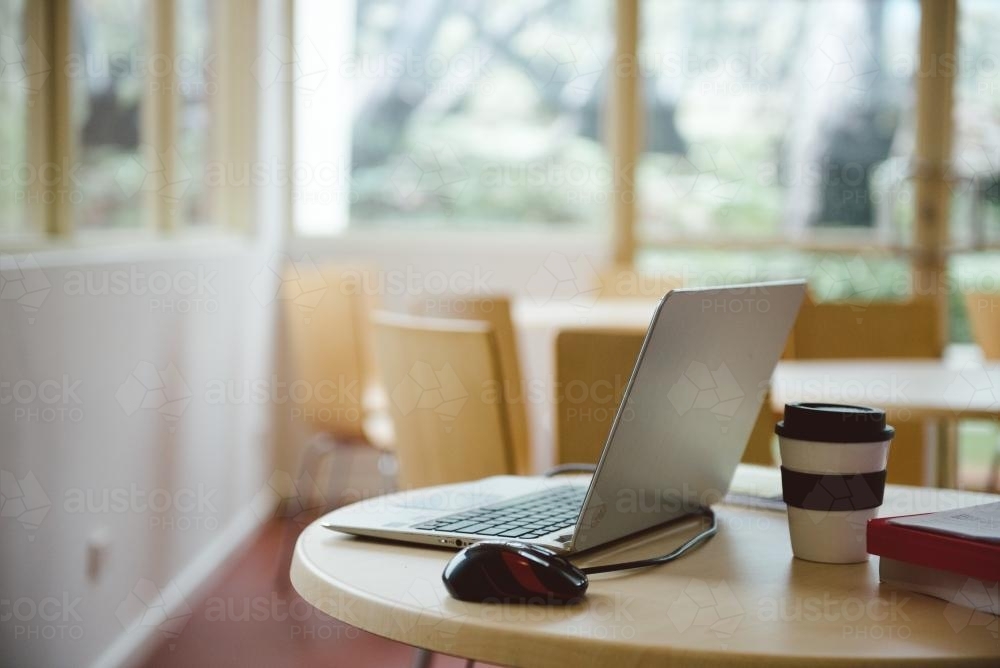 Computer on a table with take away coffee - Australian Stock Image