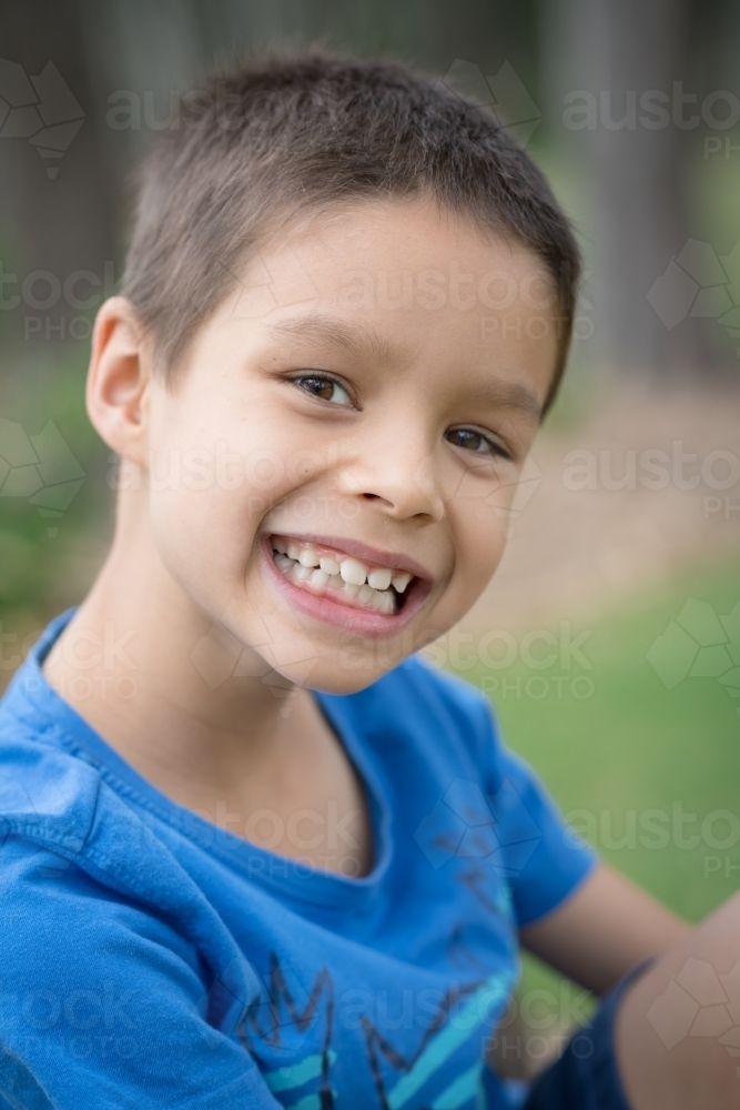 Cute mixed race boy playing in a park outside among the trees - Australian Stock Image