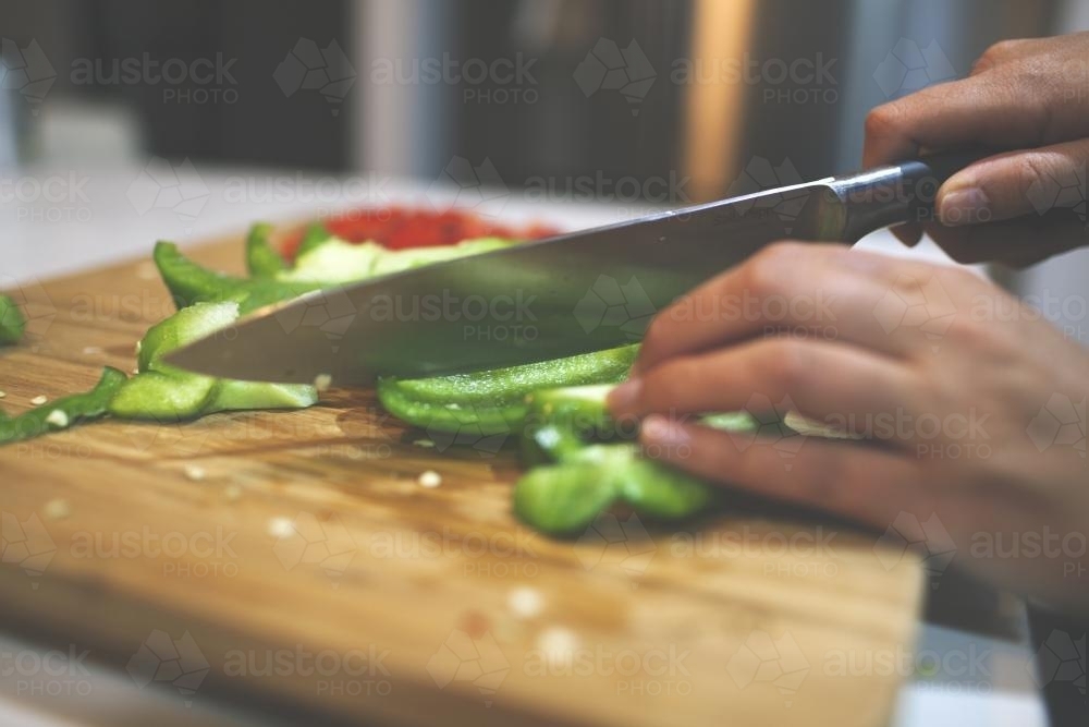 Cutting capsicum on a board - Australian Stock Image