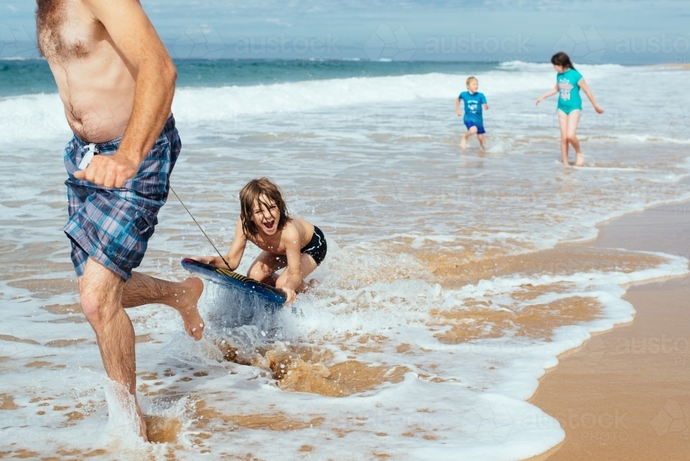 Dad tows boy on boogie board - Australian Stock Image