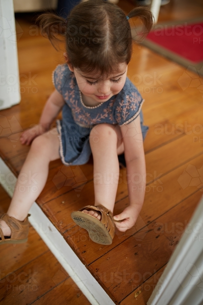 Female toddler girl putting shoes on - Australian Stock Image