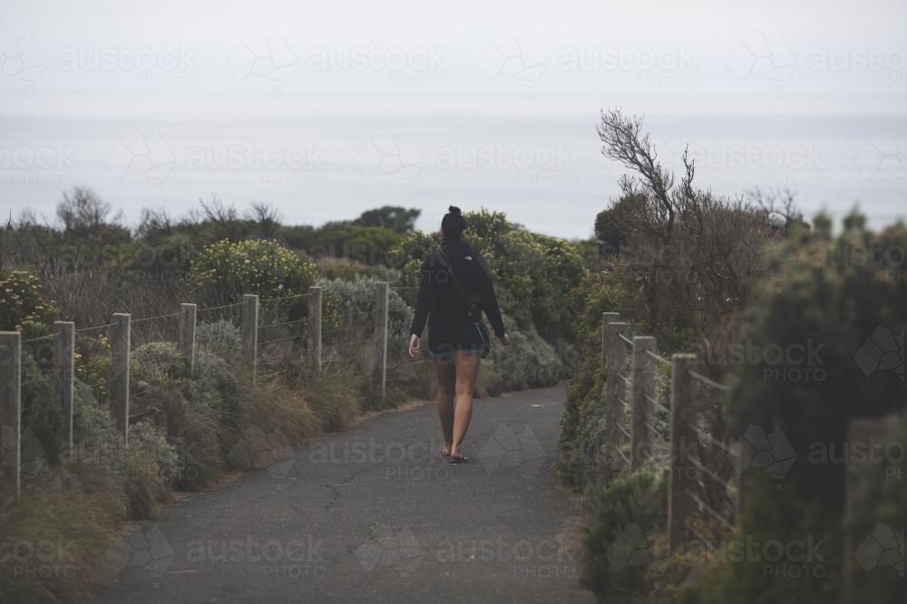 Female walking on path to beach - Australian Stock Image