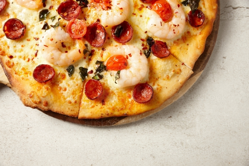 Gourmet wood fired prawn and sausage pizza on table - Australian Stock Image