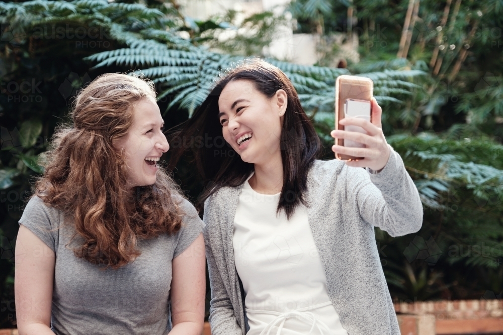 Happy students girl friends using mobile - Australian Stock Image