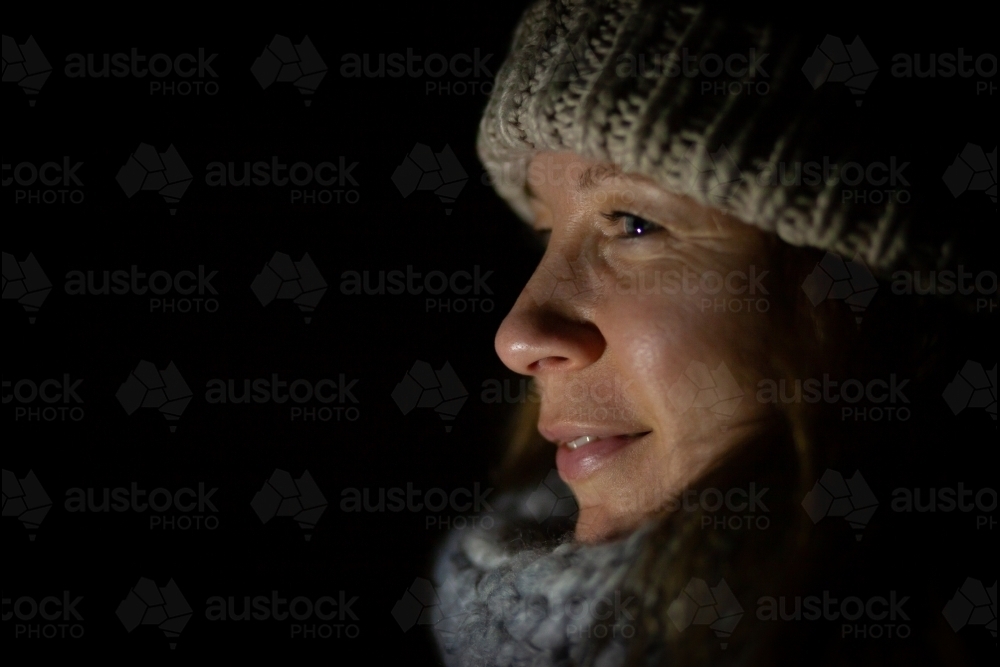 horizontal side view shot of a woman in winter clothes at night - Australian Stock Image