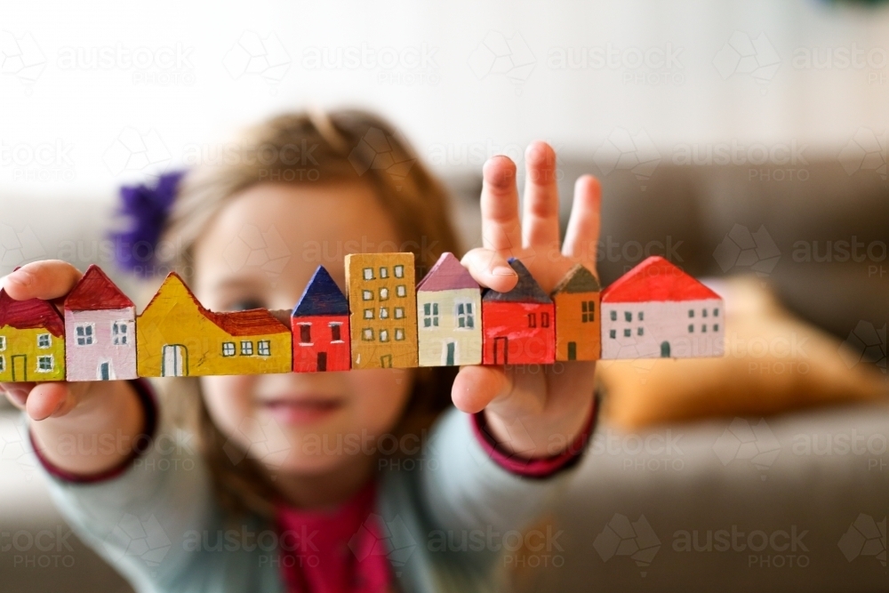 Housing affordability with a family concept shown with child holding blocks of coloured homes - Australian Stock Image