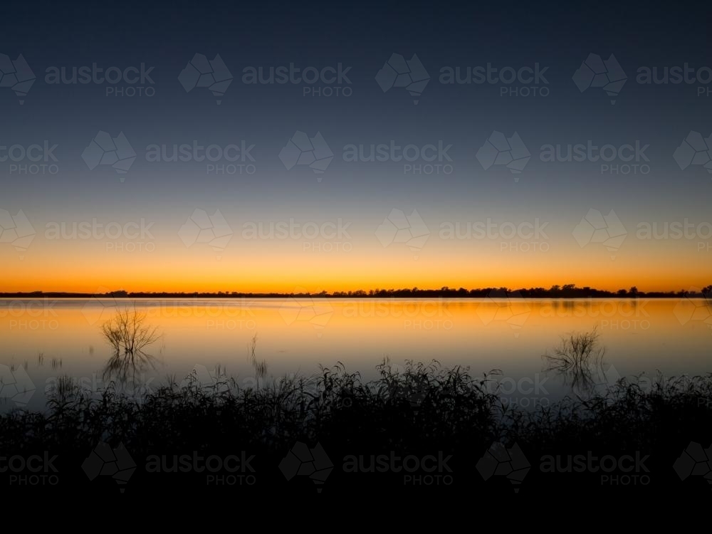 Lake with a sunset glow reflected along the horizon - Australian Stock Image
