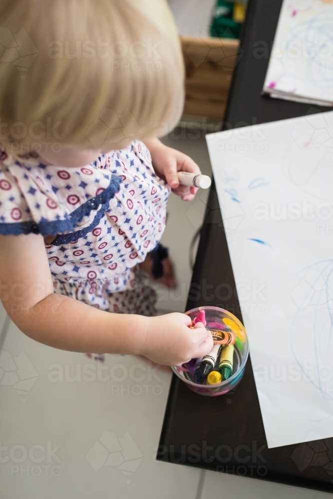 Looking down at young girl with crayons and paper - Australian Stock Image