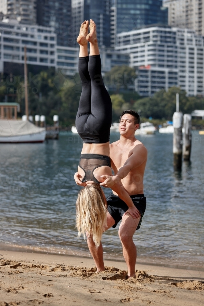 Man and woman practising acrobatics on beach - Australian Stock Image