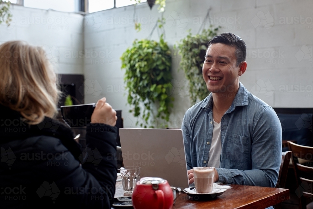 Man enjoying time with friend over coffee at cafe - Australian Stock Image