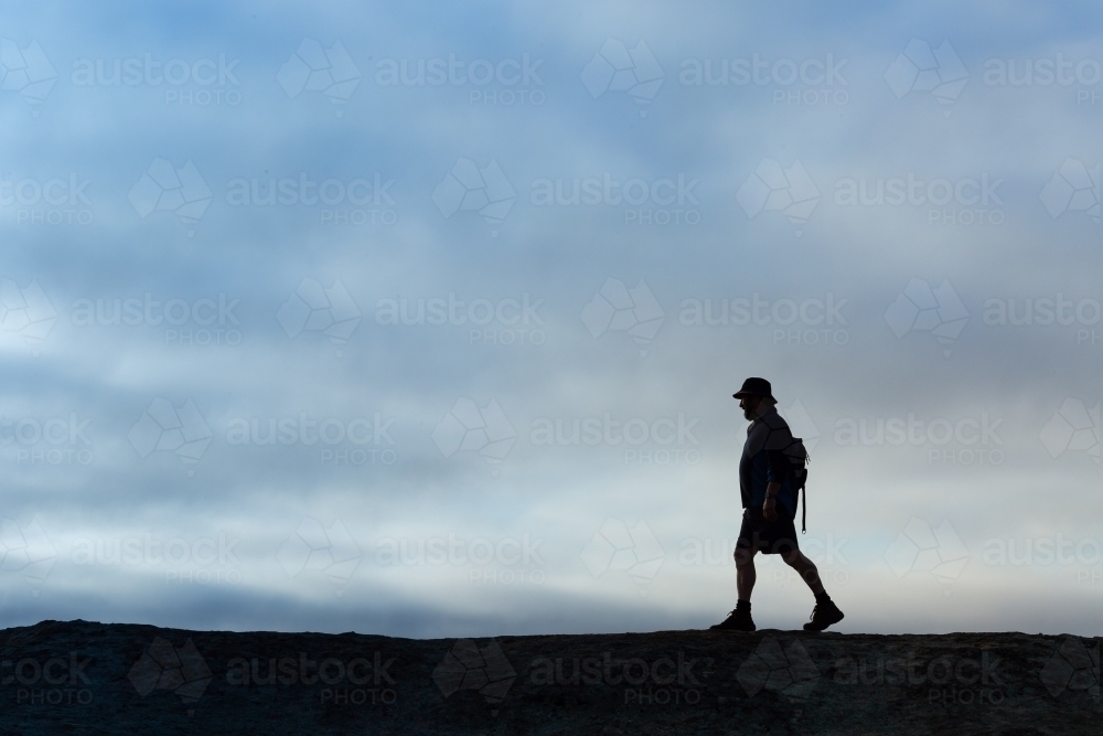 Man walking in silhouette against cloudy sky - Australian Stock Image