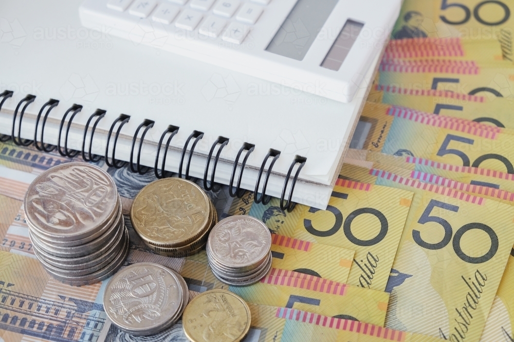 Money coins and fifty dollar notes with notebook - Australian Stock Image