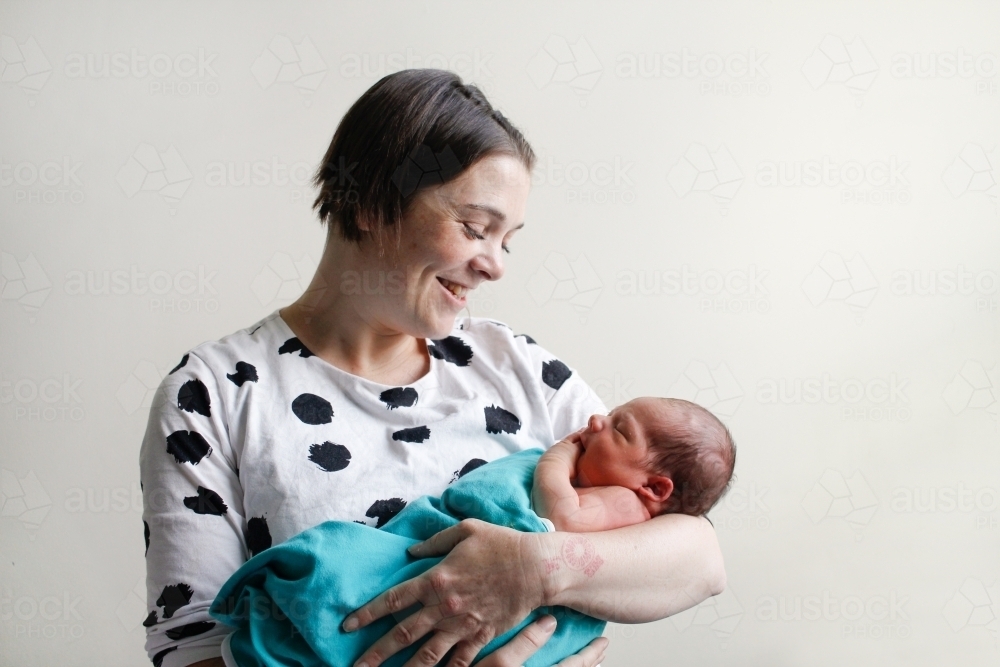 Mother holding her newborn baby, smiling - Australian Stock Image