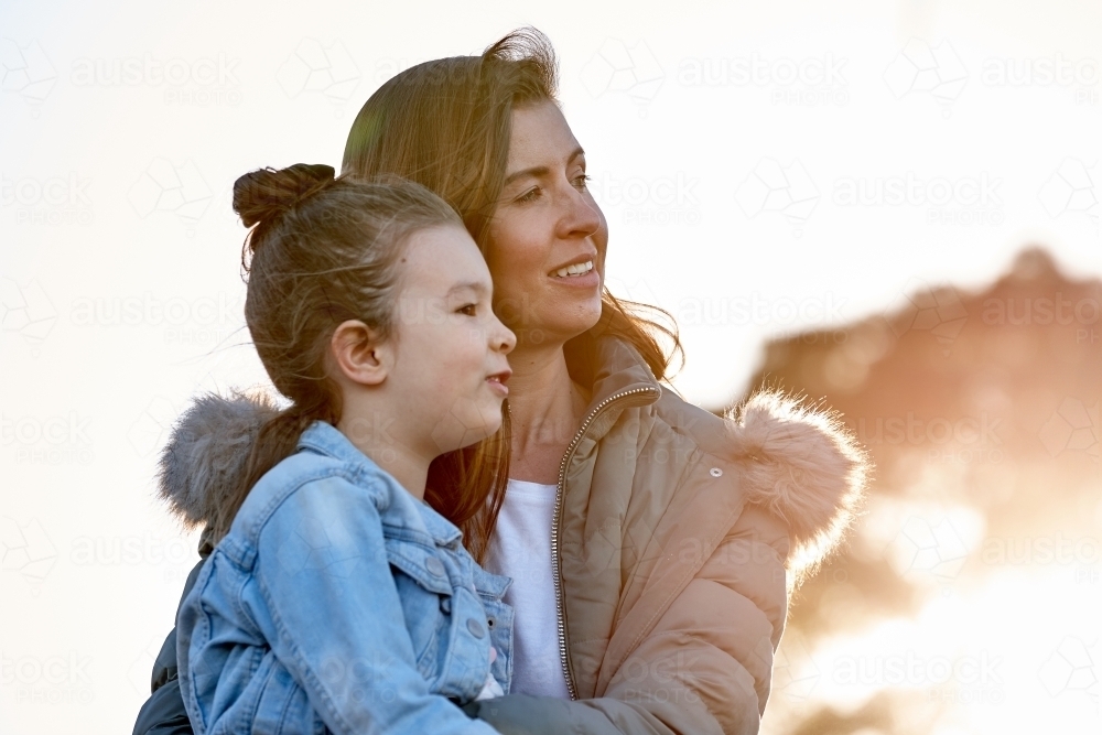Mother hugging daughter at sunset - Australian Stock Image