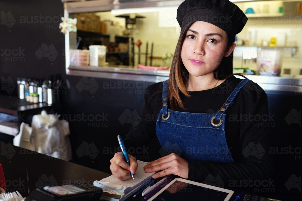 Multicultural Asian waitress taking order at Thai restaurant - Australian Stock Image