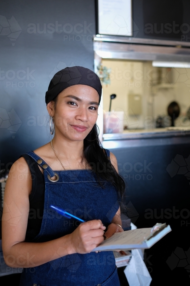 Multicultural Asian waitress taking order at Thai restaurant - Australian Stock Image