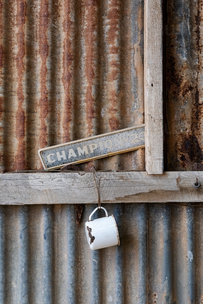 old enamel mug hanging on corrugated iron wall - Australian Stock Image