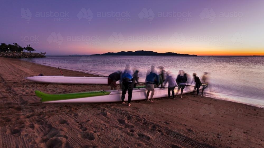 Outrigger canoe team preparing for a dawn training paddle. - Australian Stock Image