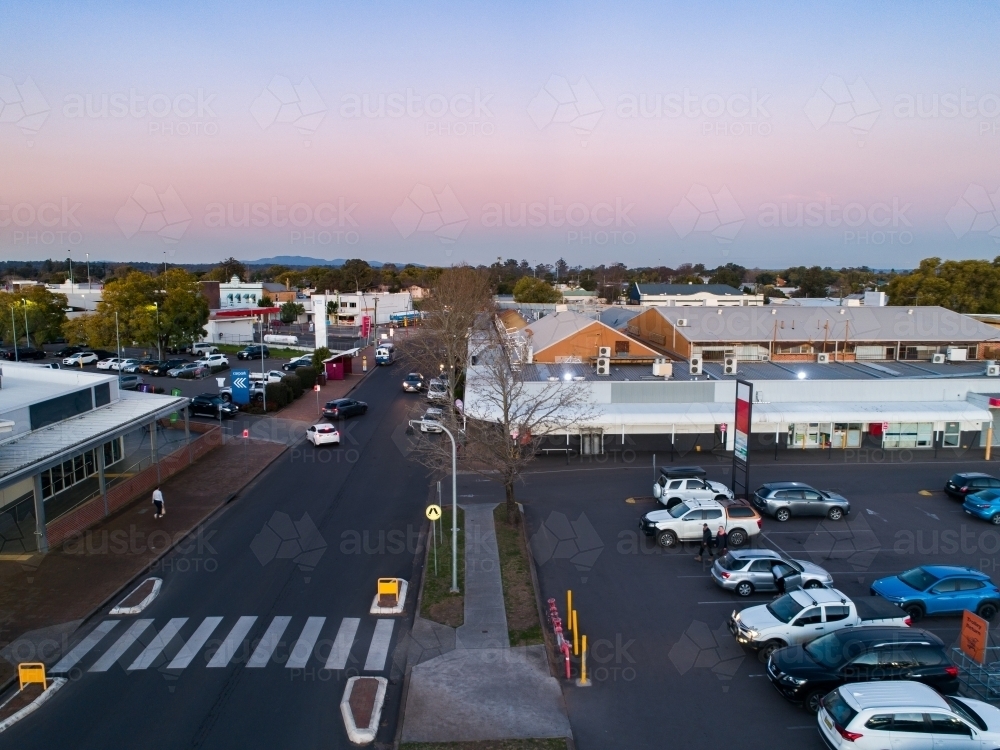 Pedestrian crossing between carpark and shopping centre in town at dusk seen from aerial view - Australian Stock Image