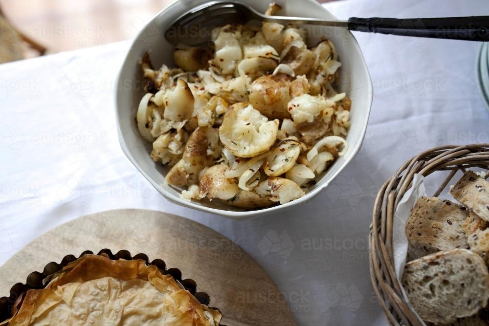 Potatoes, pie and bread rolls on table - Australian Stock Image