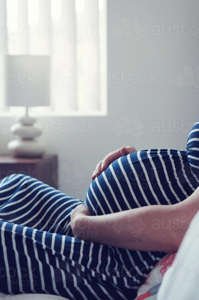 Pregnant Mother relaxing on bed - Australian Stock Image