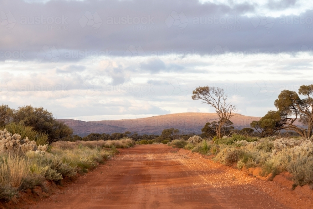 red dirt road with hills in background - Australian Stock Image