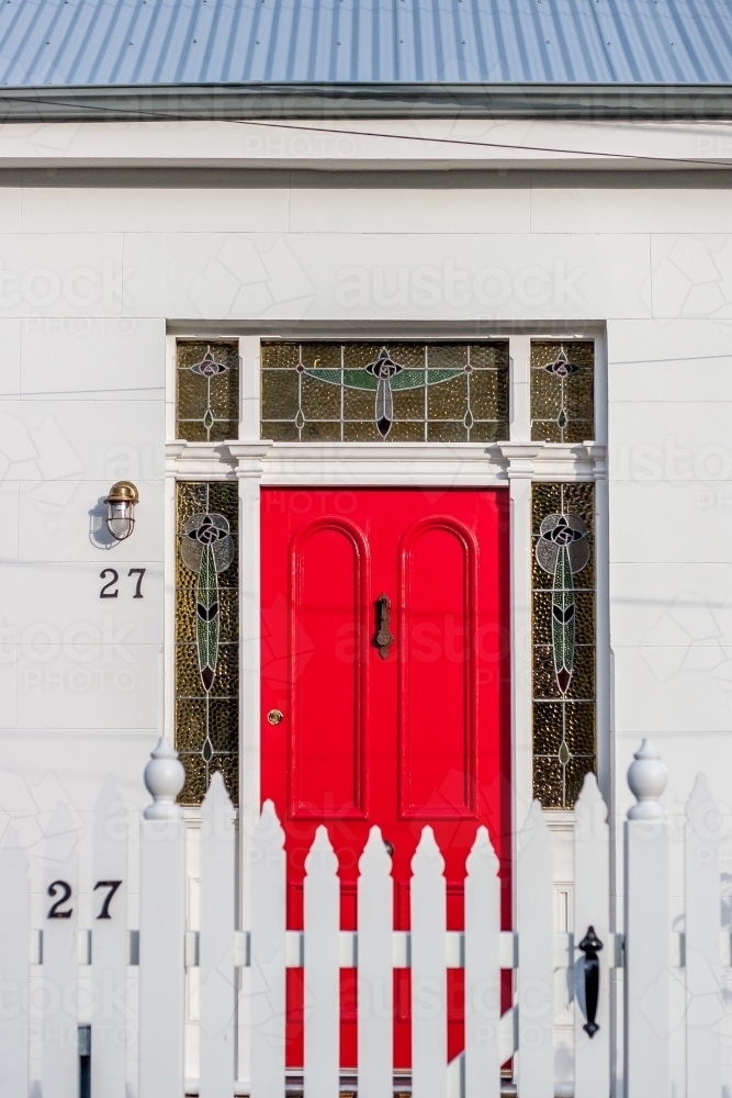 Red front door with white picket fence in urban streetscape - Australian Stock Image