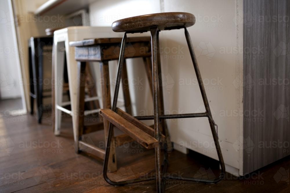 Row of miss matched stools at kitchen counter - Australian Stock Image
