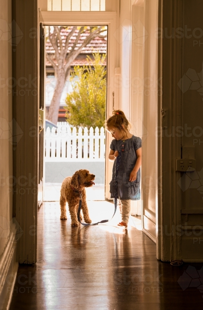 silhouette shot of a little girl with a dog on a leash in the corridor - Australian Stock Image
