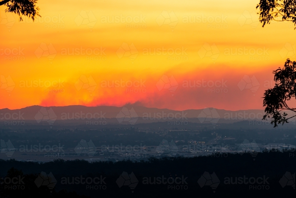 Smoke from fires on the ranges west of Brisbane, in an orange sunset - Australian Stock Image