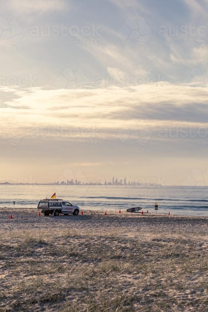 Surf Life Saving patrol ute on beach with city in background - Australian Stock Image