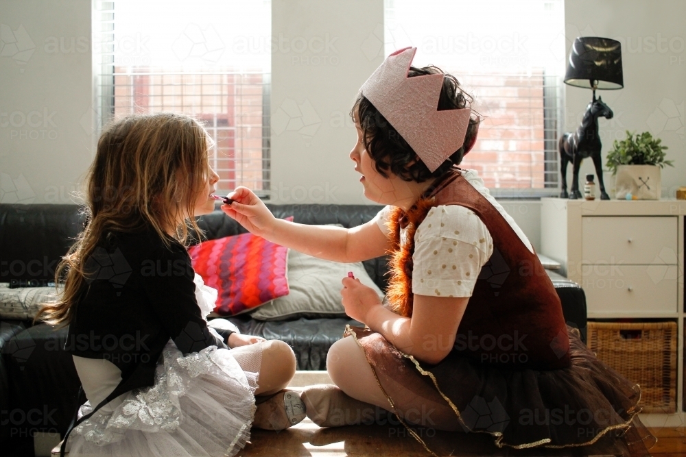 Two girls dressed as princesses playing putting on makeup - Australian Stock Image