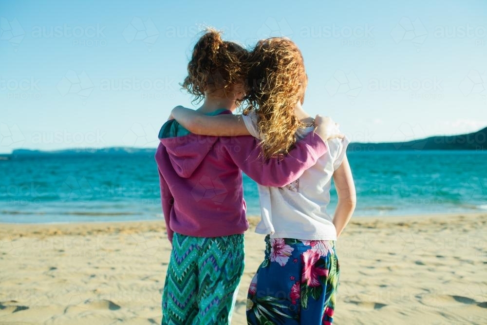 Two girls hugging at the beach - Australian Stock Image