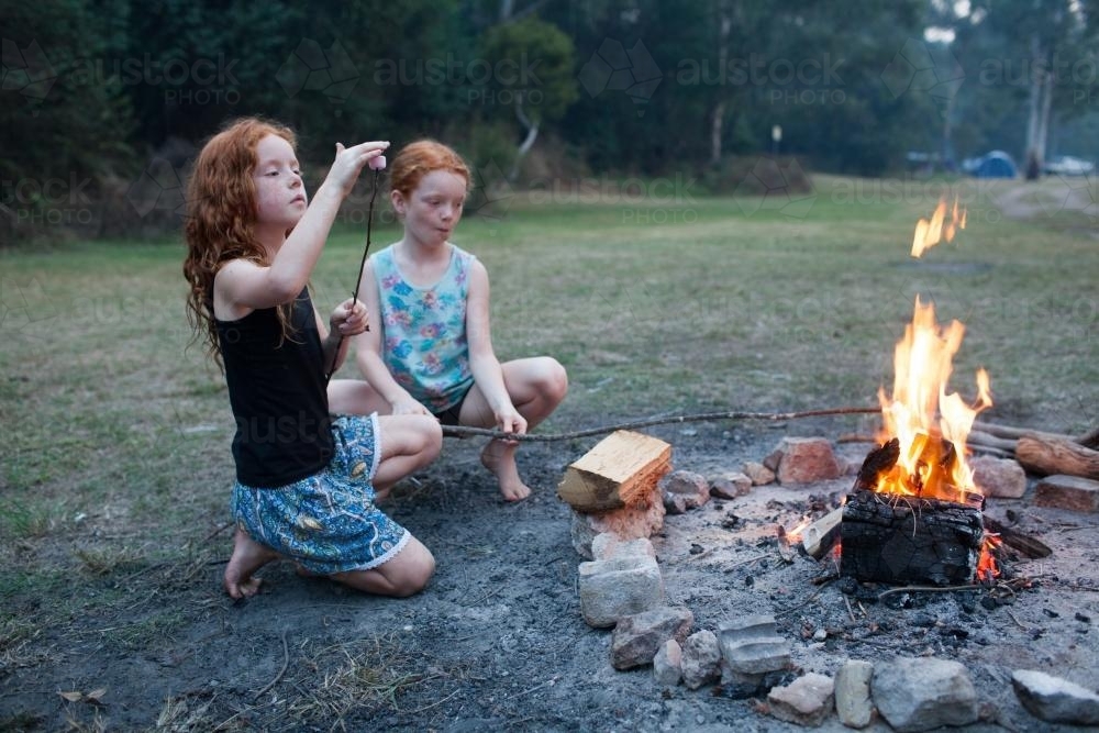 Two girls toasting marshmallows on a campfire - Australian Stock Image