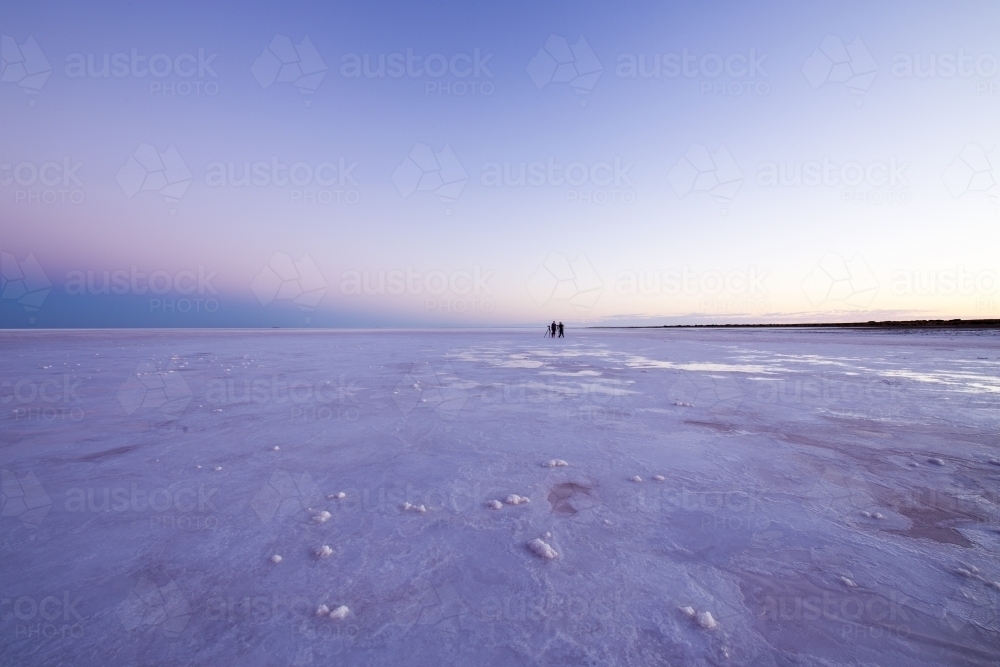 Two people in the distance on a salt lake at dawn - Australian Stock Image